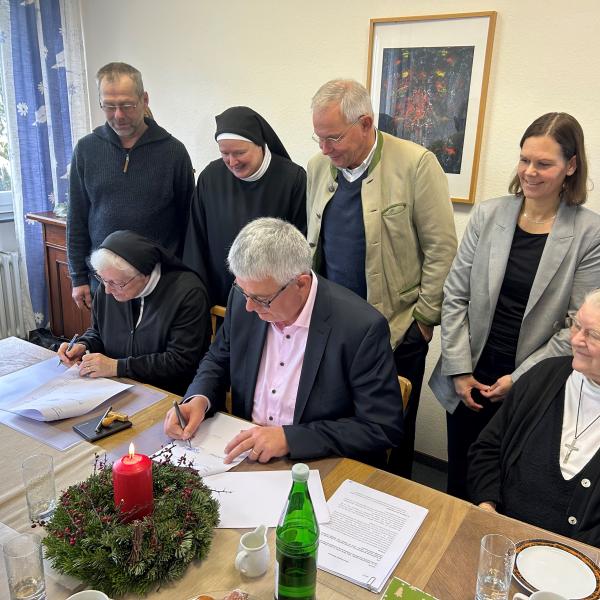16.12.2025: Unterzeichnung des Mietvertrags auf dem Rochusberg: v.l.n.r.: unser Hausmeister Herr Gurb, M. Elisabeth, Sr. Caterina, Herr Maring, Gesch&auml;ftsf&uuml;hrer der St. Hildgardishaus GgmbH, RA Dr. Kern, Frau Bretz-Stotz, Vorsitzende des St.Hildegardishaus e.V., Sr. Ancilla-Maria, Vertreterin der Kreuzschwestern (Foto: Jürgen Bolldorf)